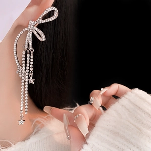 Détails de boucles d'oreilles nœud argenté avec pompons en strass et petites étoiles