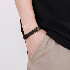 Men's woven black leather bracelet with magnetic clasp detail worn on wrist