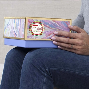 Christmas gift box with marble pattern and Merry Christmas labels in person's hand