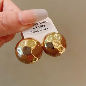Close-up of gold geometric sphere earrings with textured metal and 925 silver studs
