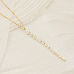 Détail d'un collier en chaîne dorée avec un élégant pendentif à pampilles de perles dégradées