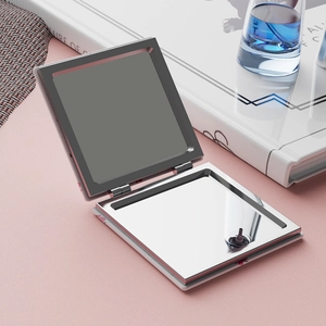 Detail view of foldable square cherry makeup mirror with silver metal frame and pink patterns