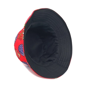 Detail view of the red bucket hat showing fruit patterns and black lining texture