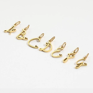 Close-up of golden A-G alphabet charms with tiny heart details on white background