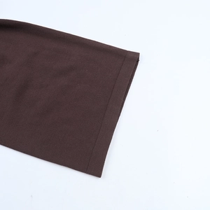 Detailed close-up of dark brown knit fabric stitching on sleeve cuffs and hemline