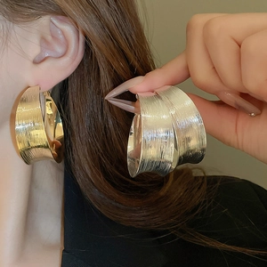 Close-up of minimalist textured hoop earrings in gold and silver with brushed finish