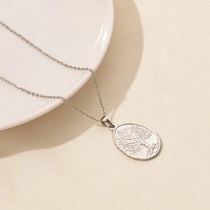 Detailed close-up of a silver Tree of Life oval pendant with a fine cable chain necklace