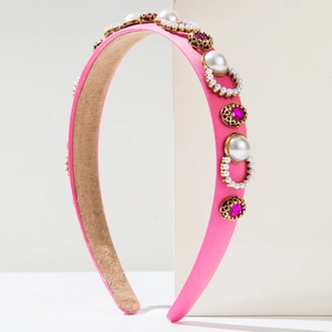 Detailed view of pink silk headband with white pearls and dark pink gemstones