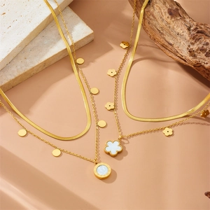 Double-layered gold stainless steel necklaces with clover and petal pendants on beige background