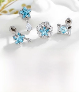 Detail of silver cartilage studs with light blue zircon star and flower designs