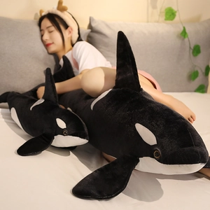 Plush orca pillows in large and small sizes shown in a cozy bedroom setting