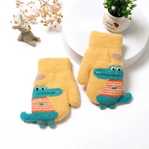 Detail of yellow knit toddler mittens featuring a cute crocodile patch and plush lining