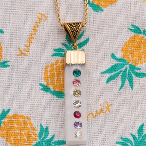 Gold chain necklace with a geometric crystal pendant and seven colorful rhinestones