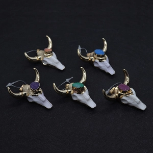 Detail of colorful resin bull head pendants with crystal inlay and golden horns on black