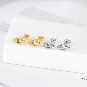 Macro shot of geometric round gold and silver earrings with inlaid purple and white zircon