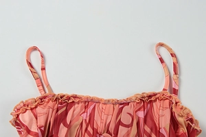 Macro shot of ruffle neckline and pink orange leaf print on a slim summer dress