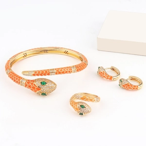 Close-up of orange enamel snake jewelry set with green gemstones and gold plating