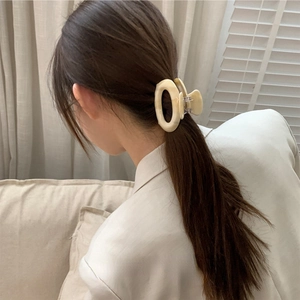 Elegant beige circular cutout acetate hair claw clip shown on model in natural light