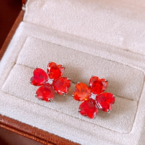 Dettaglio ravvicinato di eleganti orecchini a lobo a fiore con zirconi rossi a cuore
