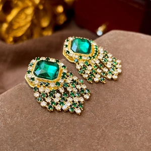 Détails de boucles d'oreilles vintage dorées avec pierre verte et pampilles en strass brillants