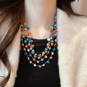 Detail of multi-layer necklace with blue and orange shell beads on female model