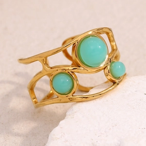 Macro detail of 18K gold plated open ring featuring three mint green gemstones on wavy band