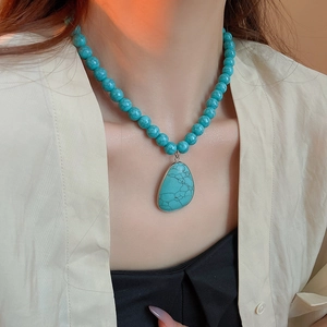 Close-up of bohemian turquoise bead necklace with a large teardrop pendant on neck