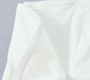 Detailaufnahme der hochwertigen Nähte auf weißem Stoff für ein figurbetontes Minikleid