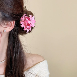 Close-up of elegant pink fabric flower hair pin worn on a model's dark hair bun