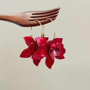 Retro red resin flower C-shape dangle earrings with gold hoops on a creative wood stand
