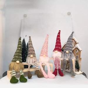 Close-up of five colorful Christmas gnomes in striped hats on a wooden bench