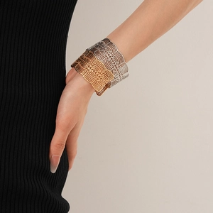 Gros plan de bracelets larges en métal ajouré style dentelle en or, argent et noir