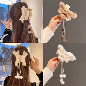 Detalle de pinza para el pelo con lazo de peluche, borlas de perlas y pompones en colores
