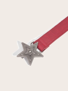 Detail of red crocodile textured leather belt with vintage silver star buckle