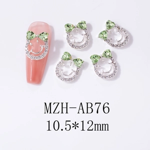 Detail of bow-knot nail charm with green heart rhinestone and silver smiley face frame