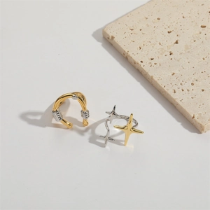 Detail of two-tone U-shape horseshoe ring and star bow rings on textured stone