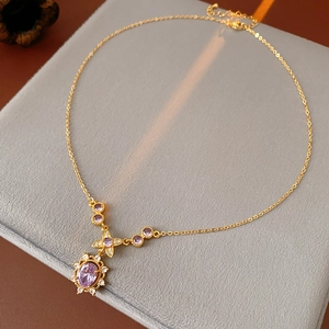 Close-up of vintage golden necklace with purple gemstone flower pendant in a velvet box