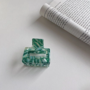Detailed view of square green marble acetate hair claw clip on white background