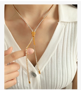 Detail of a gold zipper pendant necklace featuring sparkling white zircon stones