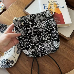 Détail de broderie de fleurs et papillons blancs sur un petit sac en lin noir