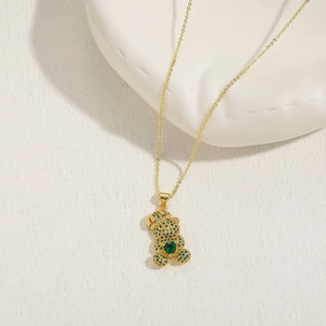 Détail du pendentif ours doré avec zircons verts et cœur sur un support céramique