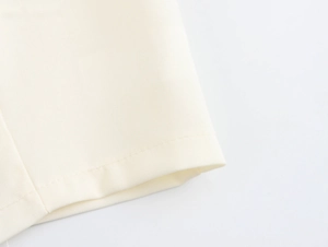 Close-up of off-white twill fabric texture and neat stitching on the garment hem
