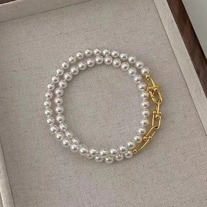 Elegant pearl and gold U-link necklace displayed in a beige jewelry gift box