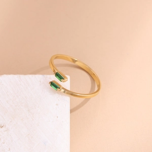 Close-up of a gold-plated open ring featuring two green rectangular stones on white stone