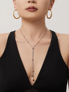 Vue détaillée du collier en Y bicolore et des boucles d'oreilles créoles portés par le mannequin