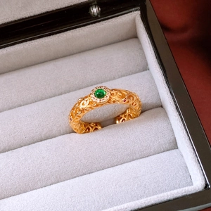Macro detail of a 24k gold plated vintage open ring with green stone in a jewelry box