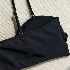 Dettaglio del top bikini nero con spalline regolabili e design con arricciature
