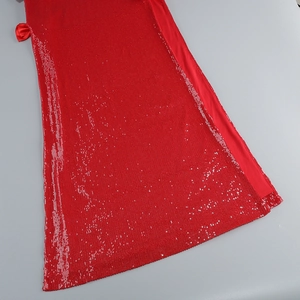 Close-up of red sequined dress featuring shimmering fabric and a satin bow detail