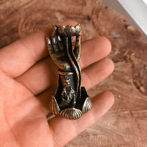 Close-up of a mini brass Buddha hand lotus incense holder held in hand for scale