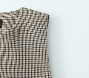 Vue détaillée de la couture d'épaule de ce gilet sans manches à carreaux marron pour femmes